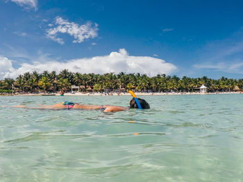 Woman snorkeling in sea against blue sky