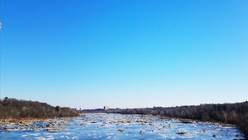 Scenic view of lake against clear blue sky during winter