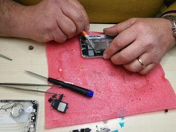 Cropped image of hand soldering smart phone at table