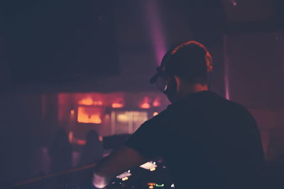Rear view of dj playing music at nightclub