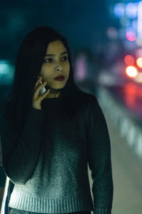 Close-up portrait of young woman standing at night