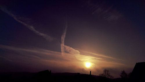 Silhouette vapor trail against sky during sunset