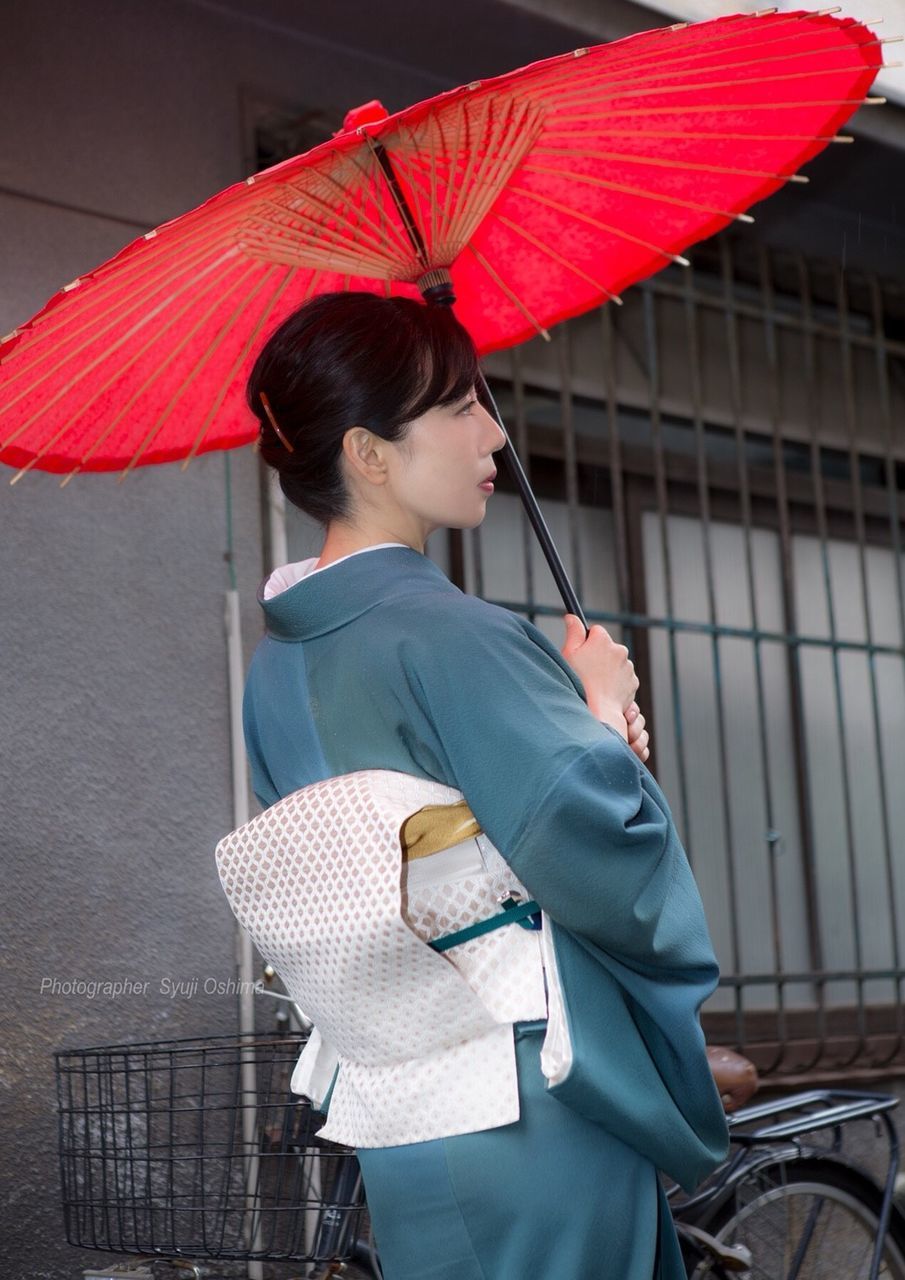 one person, women, real people, adult, holding, young adult, lifestyles, young women, umbrella, three quarter length, leisure activity, architecture, standing, building exterior, casual clothing, focus on foreground, hairstyle, beautiful woman, outdoors