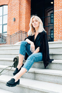 Full length of young woman sitting on staircase