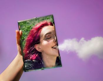 Portrait of young woman using mobile phone against sky