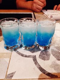 Cropped image of hand holding drink at swimming pool