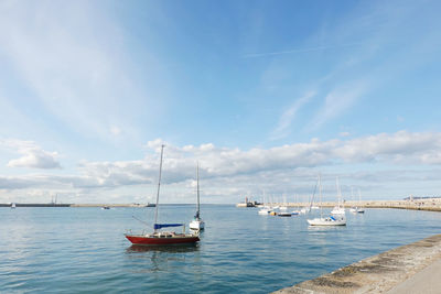 Sailboats moored on sea against sky