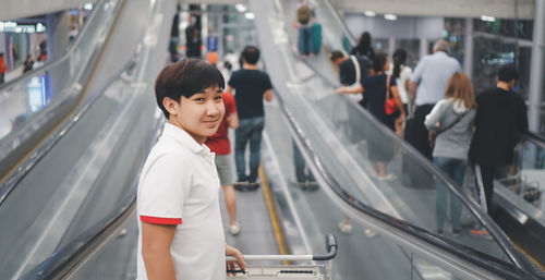 Asian young man standing on escalator in the airport. a passenger walk, indoor portrait.