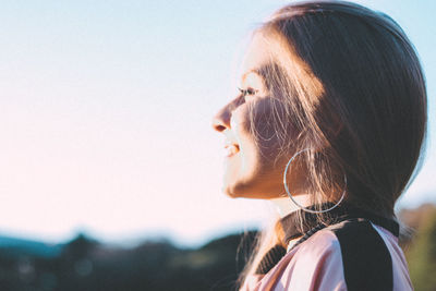 Side view of smiling young woman against sky