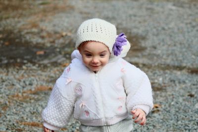 Cute smiling girl wearing knit hat while standing at beach