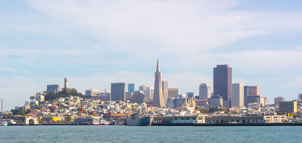 Sea by buildings against sky in city