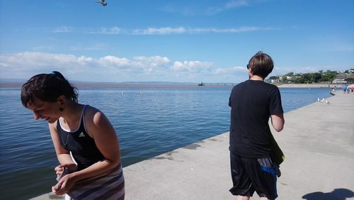 Rear view of boys standing at beach against sky