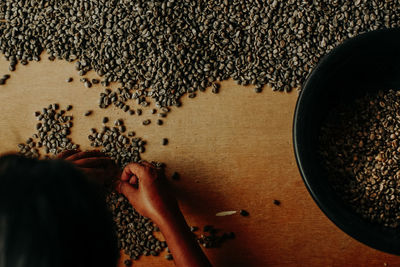 Woman with raw coffee beans on table