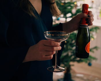 Midsection of woman holding glass and wine bottle