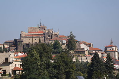 Trees and buildings against clear sky