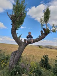 Man standing by tree on field against sky