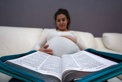 Young woman sitting on book at home