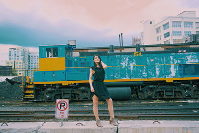 Full length of young woman standing against train in city