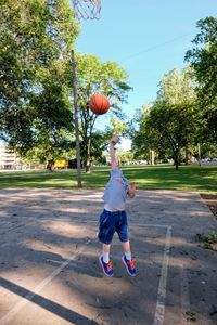 Boy playing with basketball hoop against sky