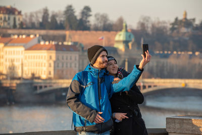 Young man photographing with mobile phone in winter