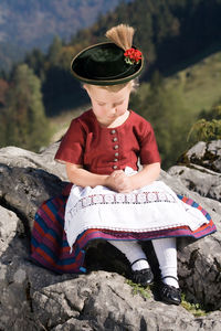 Girl in traditional clothing sitting on rock