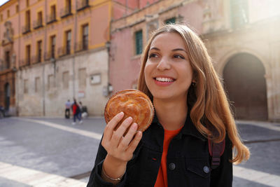 Beautiful tourist girl holding pastel murcian meatloaf in murcia street, spain.