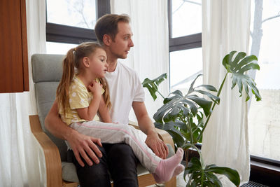 Father with daughter sitting in armchair