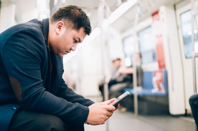 Side view of young man using mobile phone