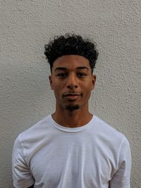 Portrait of young man standing against wall