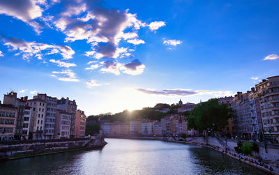 City at waterfront against cloudy sky