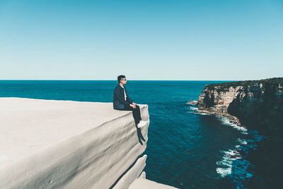 Young man standing on beach against clear sky