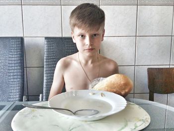 Portrait of boy sitting on table at home