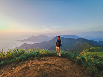 Rear view of man standing on mountain against sky