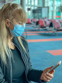 Senior woman wearing mask using smart phone outdoors