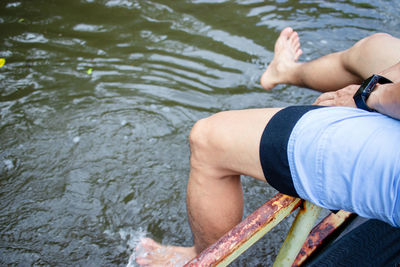 Low section of man relaxing over lake