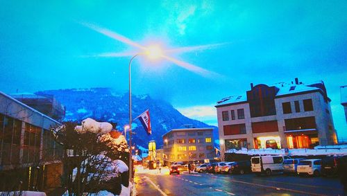 Illuminated city street against blue sky