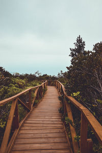 Wooden footbridge on footpath against sky