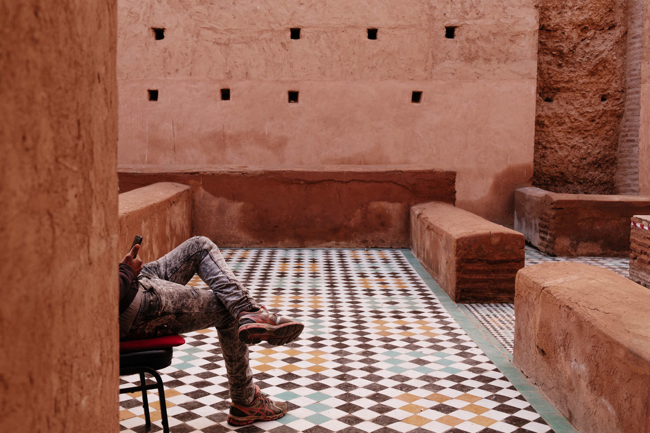 WOMAN SITTING ON CHAIR AGAINST BUILDING