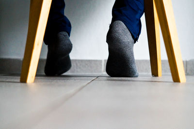 Low section of man wearing sock while sitting on table at home