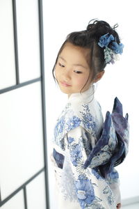 Portrait of smiling girl standing against wall