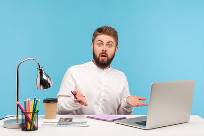 Man working on table against blue background