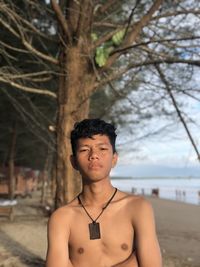 Portrait of shirtless young man standing on beach