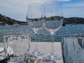 Close-up of wine glasses on table against sky