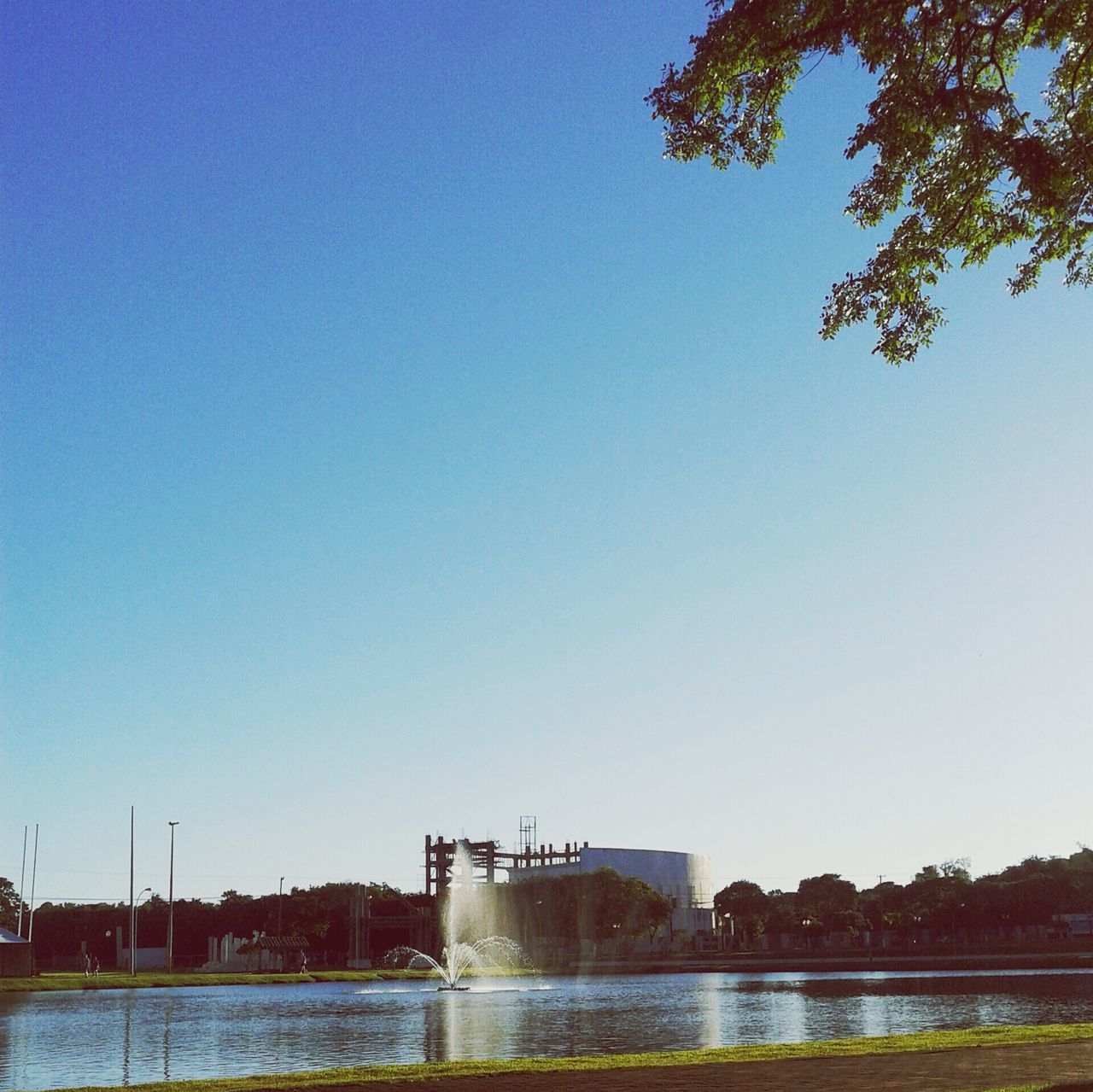 clear sky, copy space, water, built structure, blue, architecture, river, waterfront, bridge - man made structure, tree, connection, lake, building exterior, tranquility, bridge, nature, outdoors, tranquil scene, reflection, travel destinations