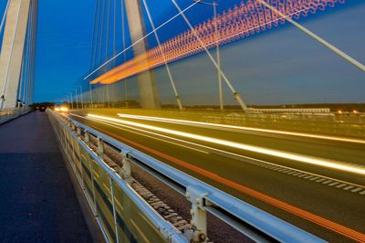 Light trails on suspension bridge against sky in city