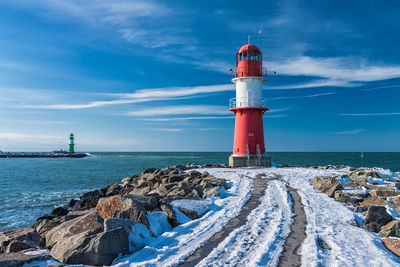 Lighthouse by sea against sky