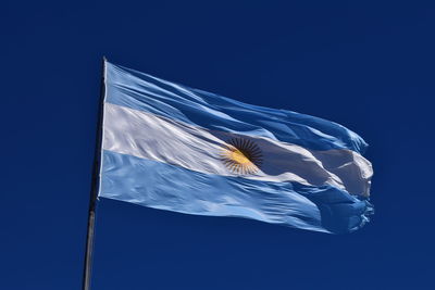 Low angle view of argentinean flag against blue sky