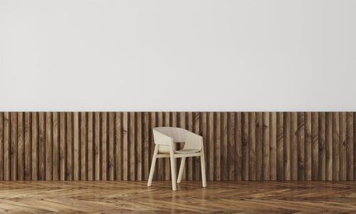 Empty chairs and tables on hardwood floor against wall at home