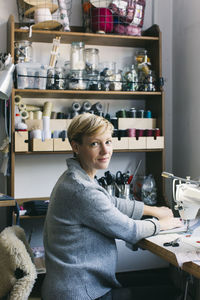 Portrait of confident woman using sewing machine in studio