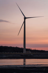 Wind turbines on landscape against sky during sunset